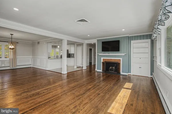 an empty room with wooden floor fireplace and windows
