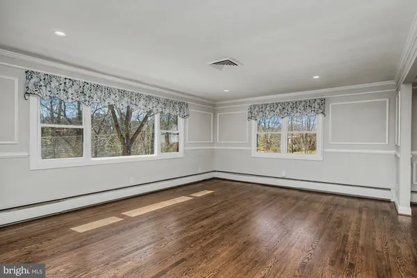 an empty room with wooden floor and windows