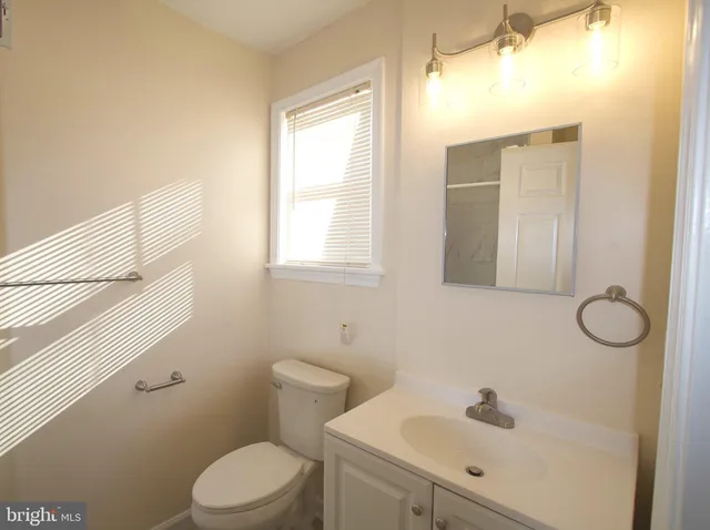 a bathroom with a toilet sink vanity and mirror