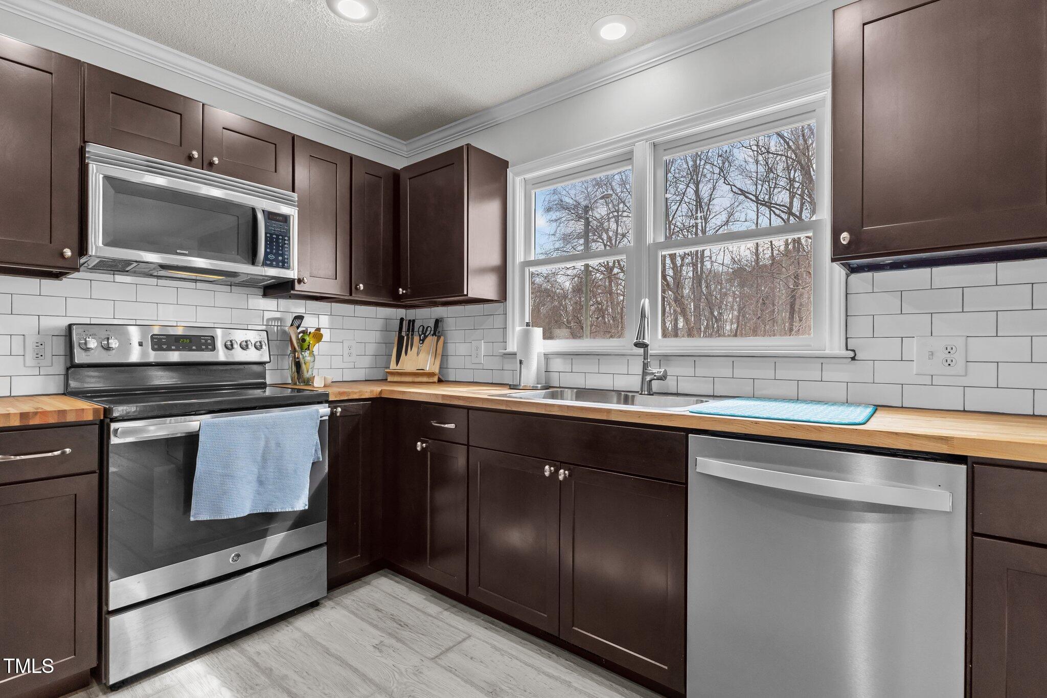 3068 Benson Road Angier, NC 27501 - Photo 13 of 52 a kitchen with stainless steel appliances granite countertop a stove sink microwave and window
