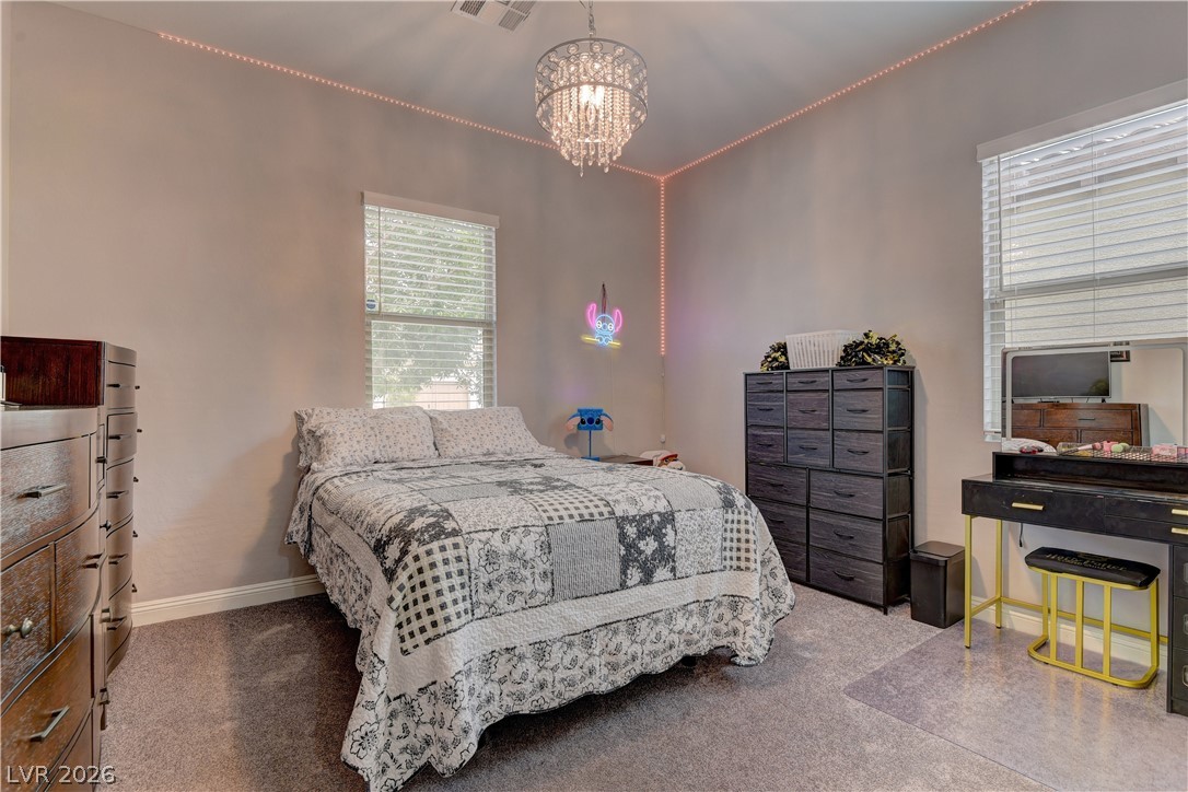 5967 Yellow Ridge Avenue Las Vegas, NV 89131 - Photo 22 of 33 This cozy bedroom features carpeted flooring and a charming chandelier, creating a comfortable living space.