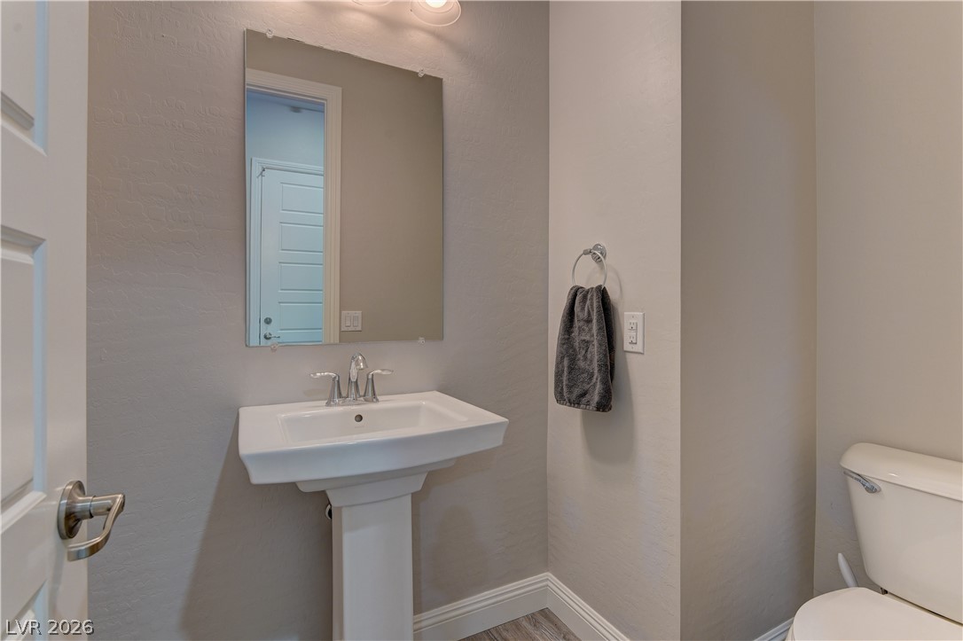 5967 Yellow Ridge Avenue Las Vegas, NV 89131 - Photo 26 of 33 This bathroom features a contemporary pedestal sink and a sleek wall-mounted mirror, perfect for daily routines.