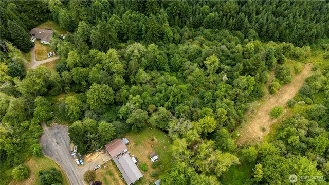 an aerial view of residential house with outdoor space and trees all around
