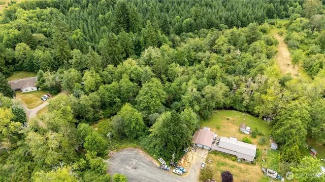 an aerial view of residential house with outdoor space and trees all around