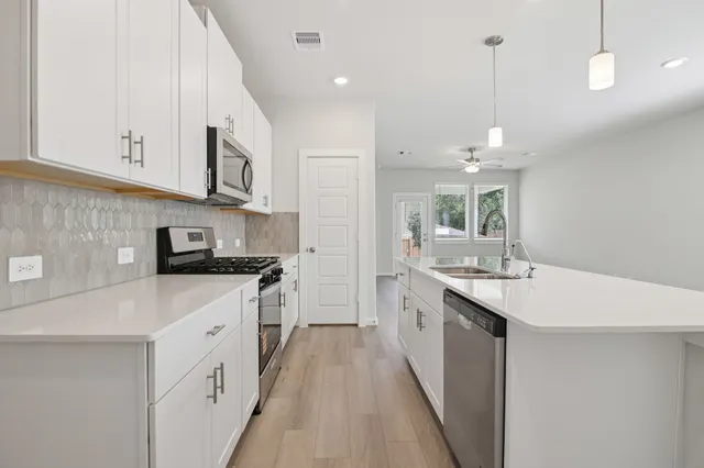 a kitchen with stainless steel appliances granite countertop a sink a stove and a refrigerator