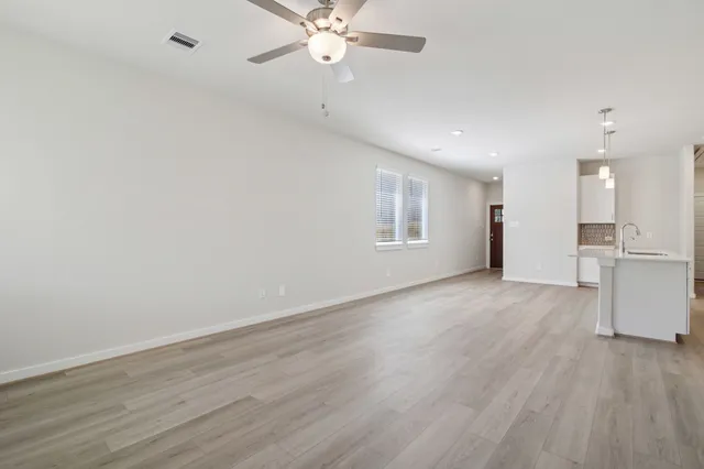 a view of an empty room with a window and wooden floor