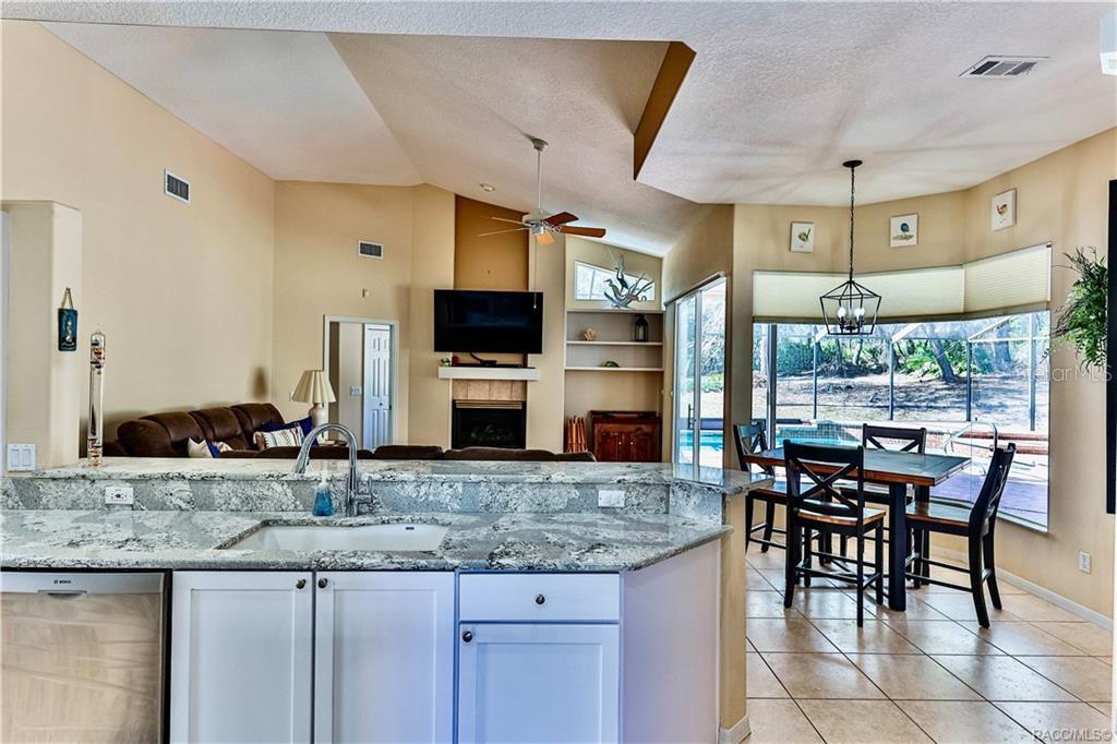 5420 North Rosedale Circle Beverly Hills, FL 34465 - Photo 13 of 49 a kitchen with granite countertop a table chairs sink and cabinets