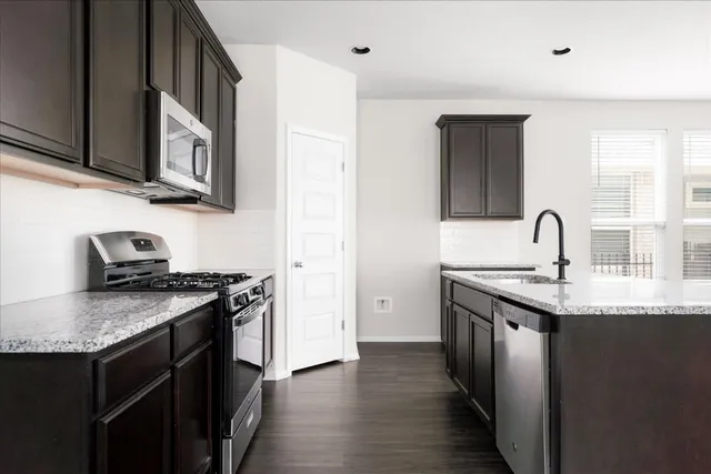 a kitchen with stainless steel appliances granite countertop a sink stove and wooden floor
