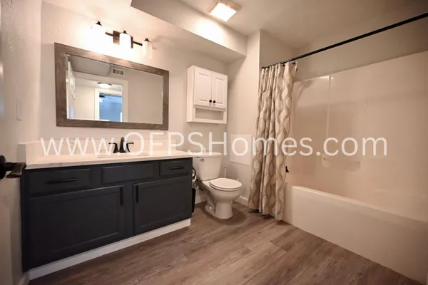 a bathroom with a granite countertop sink toilet a mirror a bathtub and shower