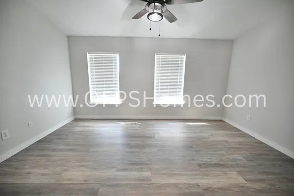 a view of an empty room with wooden floor and a window