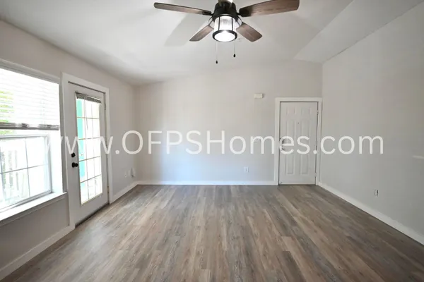 a view of an empty room with a window and wooden floor