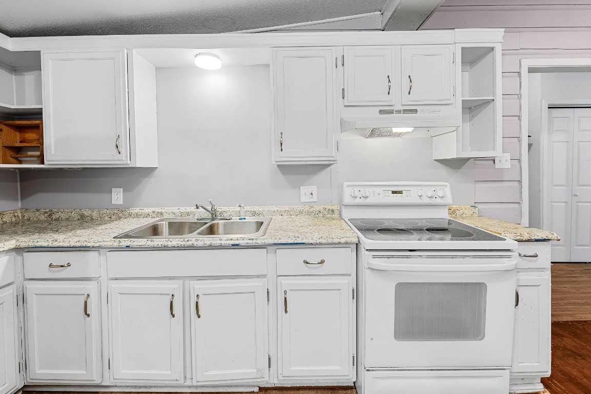 402 East 4th Street Taylor, TX 76574 - Photo 12 of 18 a kitchen with granite countertop white cabinets and a stove