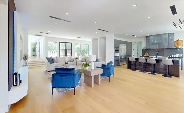 a living room with furniture and a dining table with wooden floor