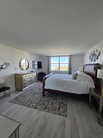 a spacious bedroom with a bed a mirror and a table in it