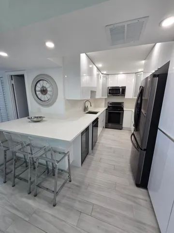 a kitchen with stainless steel appliances a table chairs in it and wooden floors