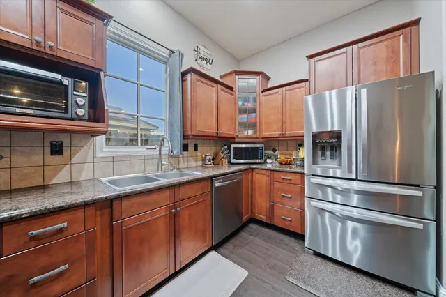 a kitchen with granite countertop stainless steel appliances a refrigerator stove and microwave