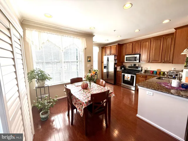 a kitchen with stainless steel appliances granite countertop wooden floors a table and chairs in it