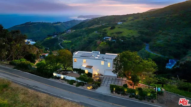 an aerial view of a house with a yard and mountain view in back