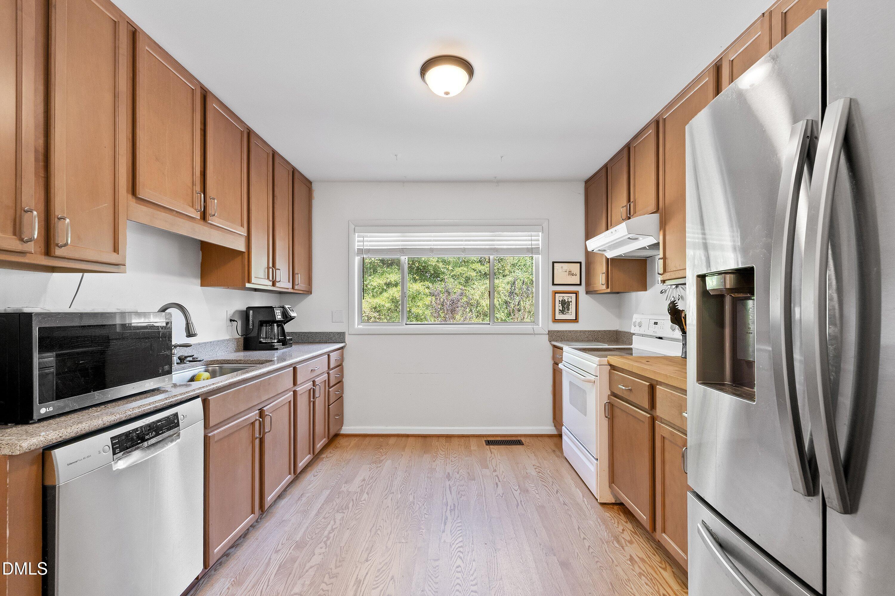 1445 Sedwick Road Durham, NC 27713 - Photo 10 of 48 a kitchen with stainless steel appliances a refrigerator sink and wooden cabinets