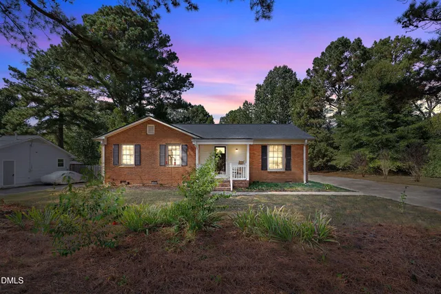 a front view of a house with a garden and trees
