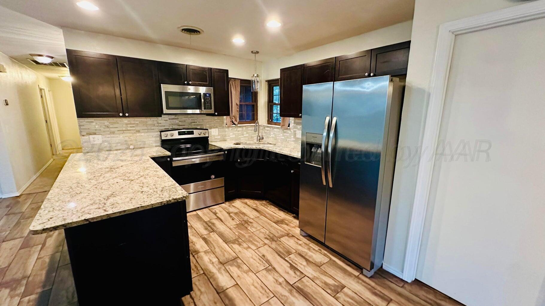 6820 Rochelle Lane Amarillo, TX 79109 - Photo 5 of 18 a kitchen with stainless steel appliances granite countertop a refrigerator a stove top oven and a sink