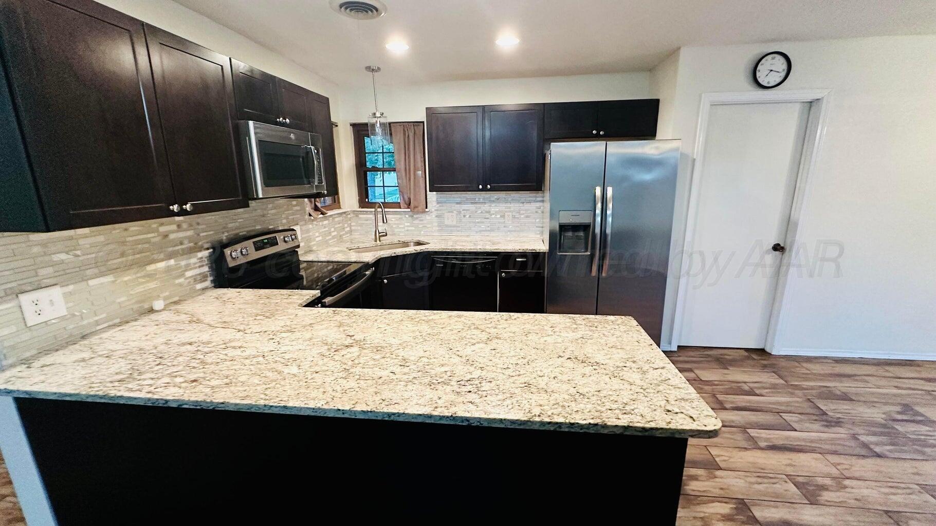 6820 Rochelle Lane Amarillo, TX 79109 - Photo 7 of 18 a bathroom with a granite countertop sink and a refrigerator