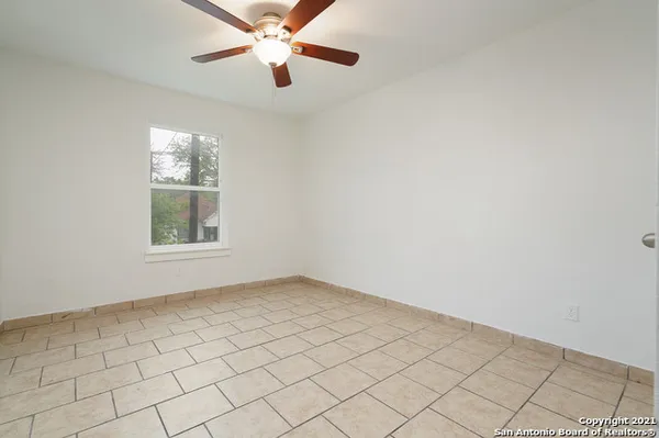 an empty room with windows and fan
