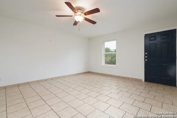 an empty room with windows and fan