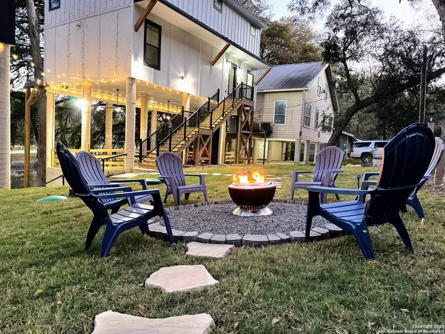 a view of a backyard with table and chairs potted plants and a bench