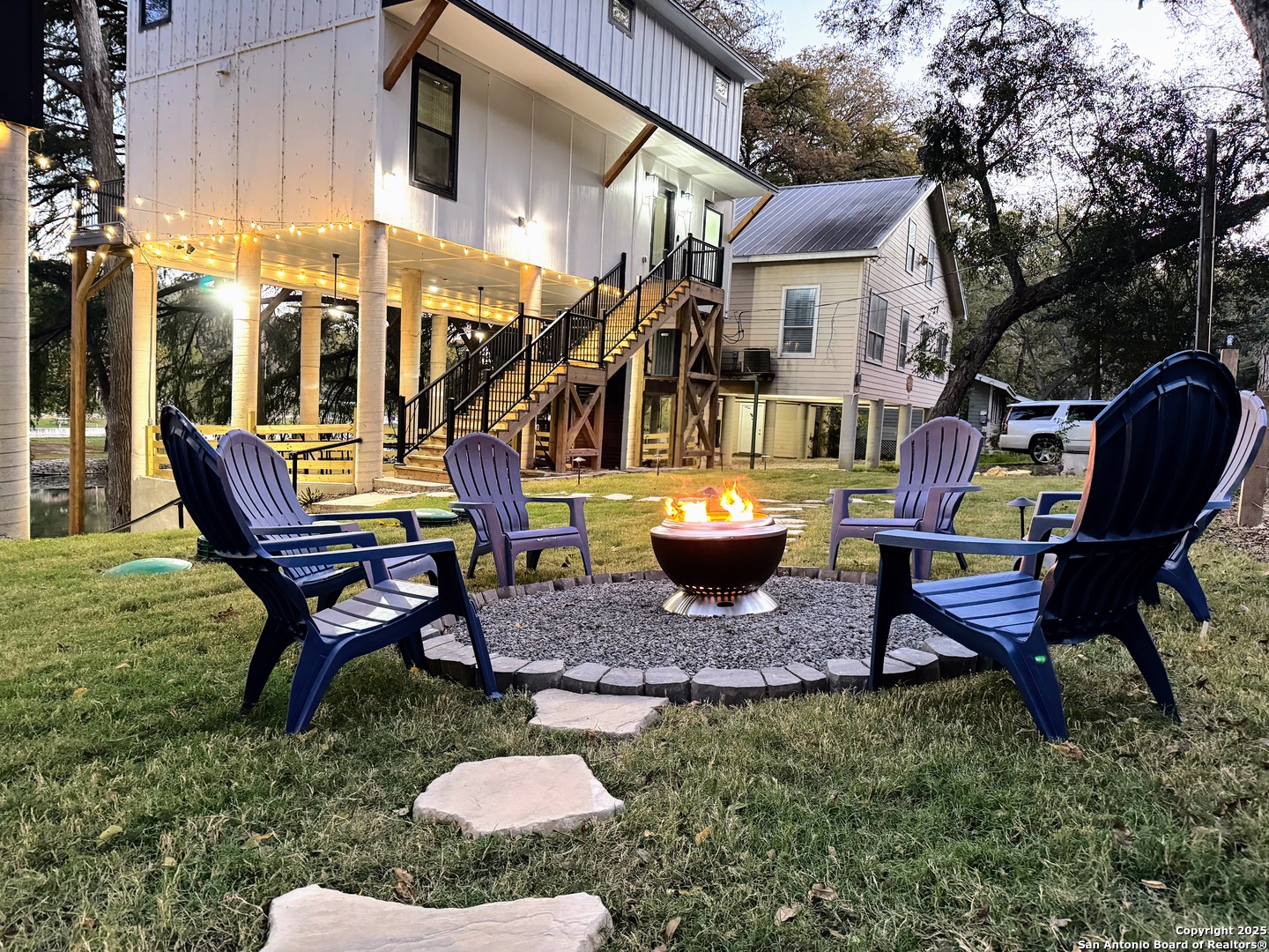 a view of a backyard with table and chairs potted plants and a bench