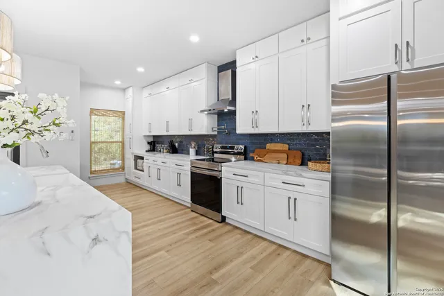a kitchen with stainless steel appliances granite countertop a refrigerator sink and white cabinets