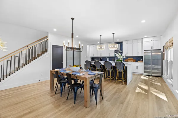 a open kitchen with stainless steel appliances granite countertop a dining table chairs refrigerator and sink