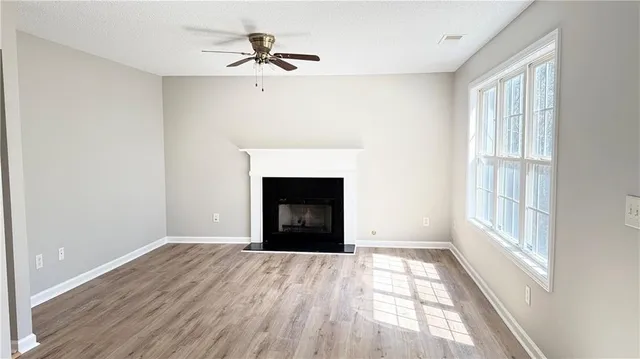a view of an empty room with a window and wooden floor