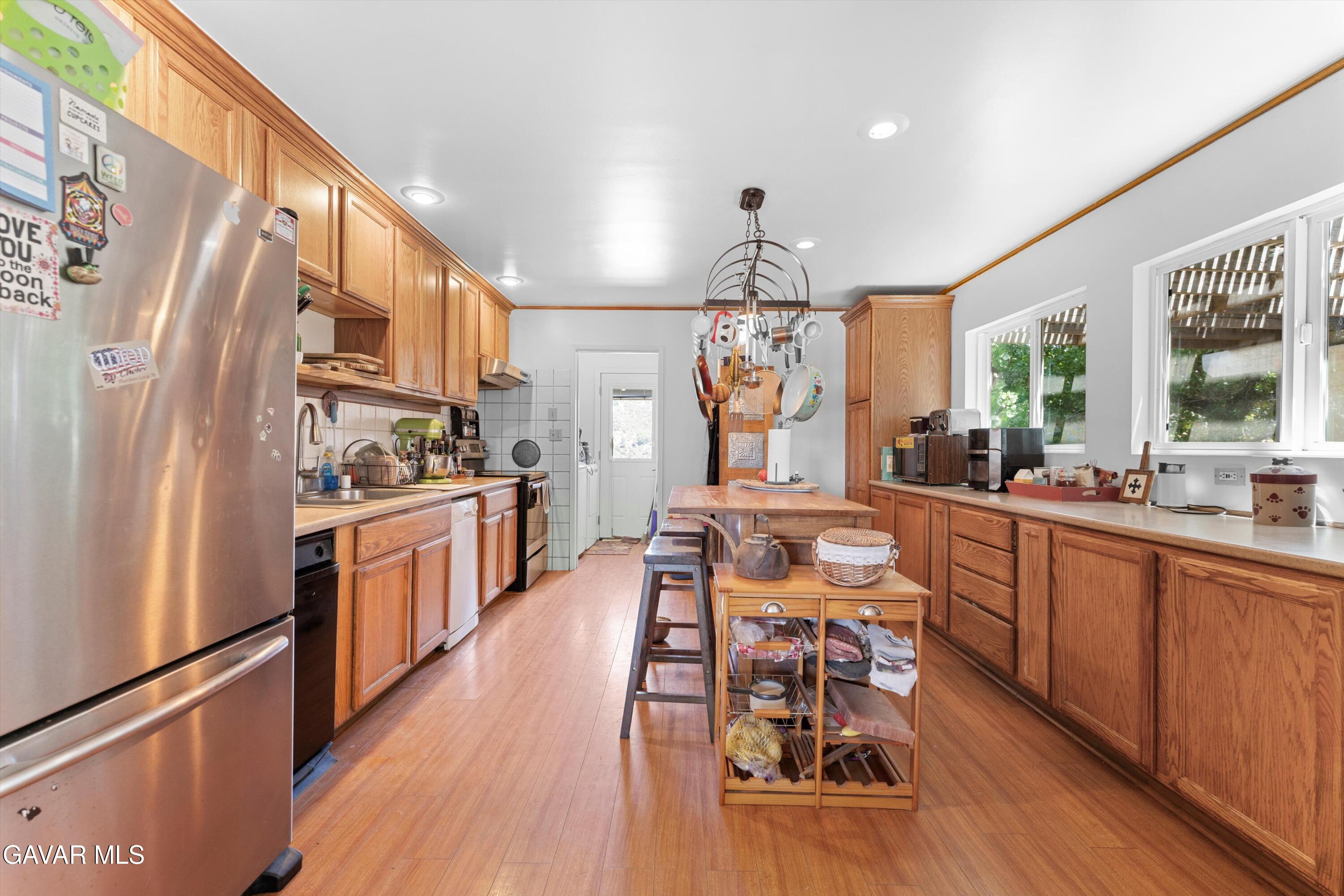 24750 Flatiron Court Tehachapi, CA 93561 - Photo 9 of 25 a kitchen with stainless steel appliances a dining table chairs refrigerator and sink