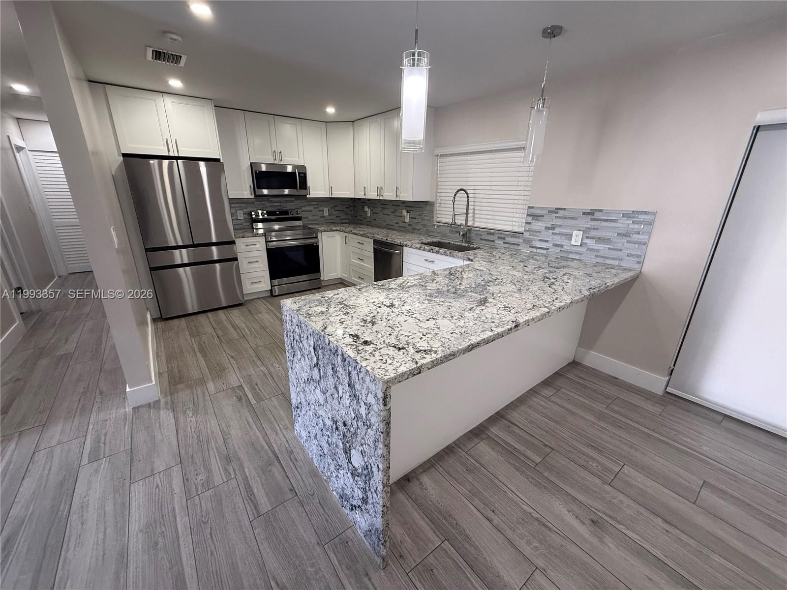 1050 West 37th Street Hialeah, FL 33012 - Photo 4 of 19 a kitchen with kitchen island wooden floors appliances and cabinets