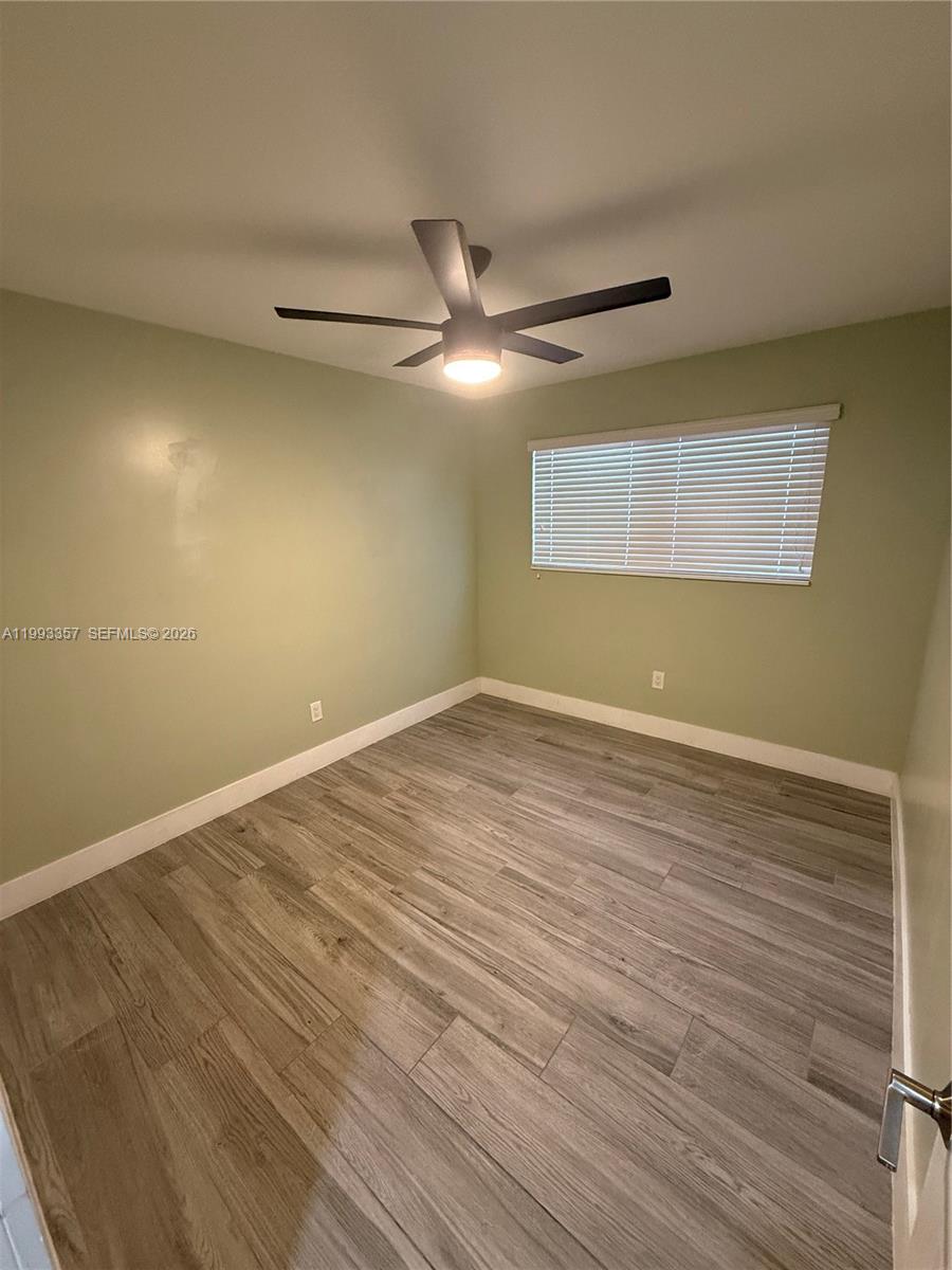 1050 West 37th Street Hialeah, FL 33012 - Photo 7 of 19 a view of an empty room with wooden floor and a ceiling fan