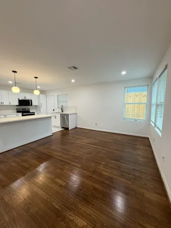 a view of kitchen and empty room with wooden floor and windows