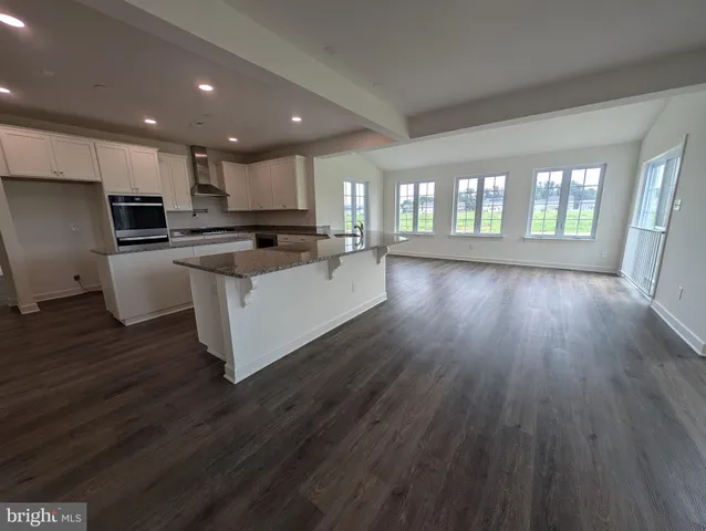 an empty room with wooden floor fireplace and windows