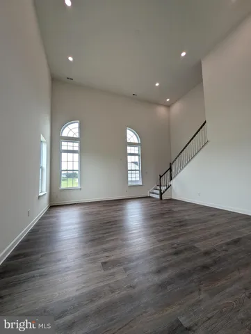 a view of an empty room with wooden floor fireplace and a window