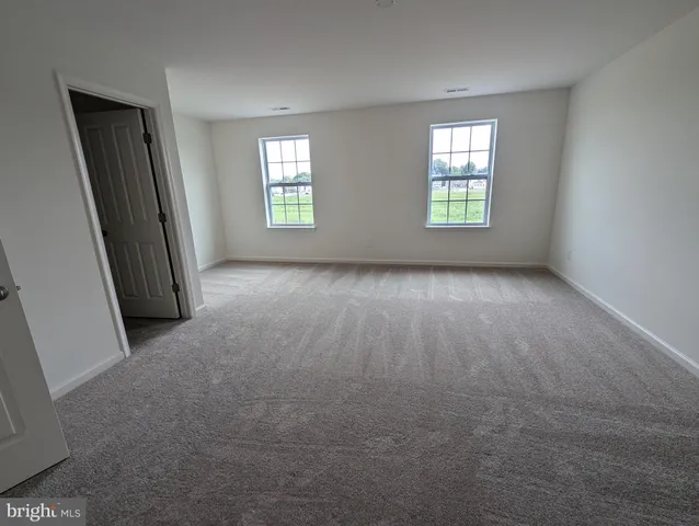 an empty room with wooden floor closet and windows