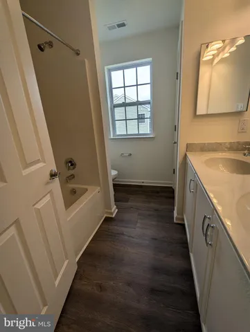 a bathroom with a tub sink vanity and mirror