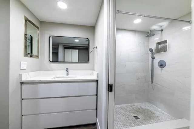 a bathroom with a granite countertop sink a mirror and shower