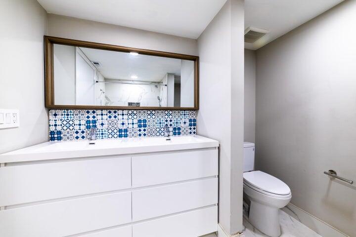 2517 Presidential Way, Unit B West Palm Beach, FL 33401 - Photo 30 of 45 a bathroom with a sink a toilet and mirror