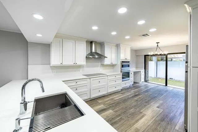 a kitchen with stainless steel appliances granite countertop a stove a sink and a refrigerator with white cabinets