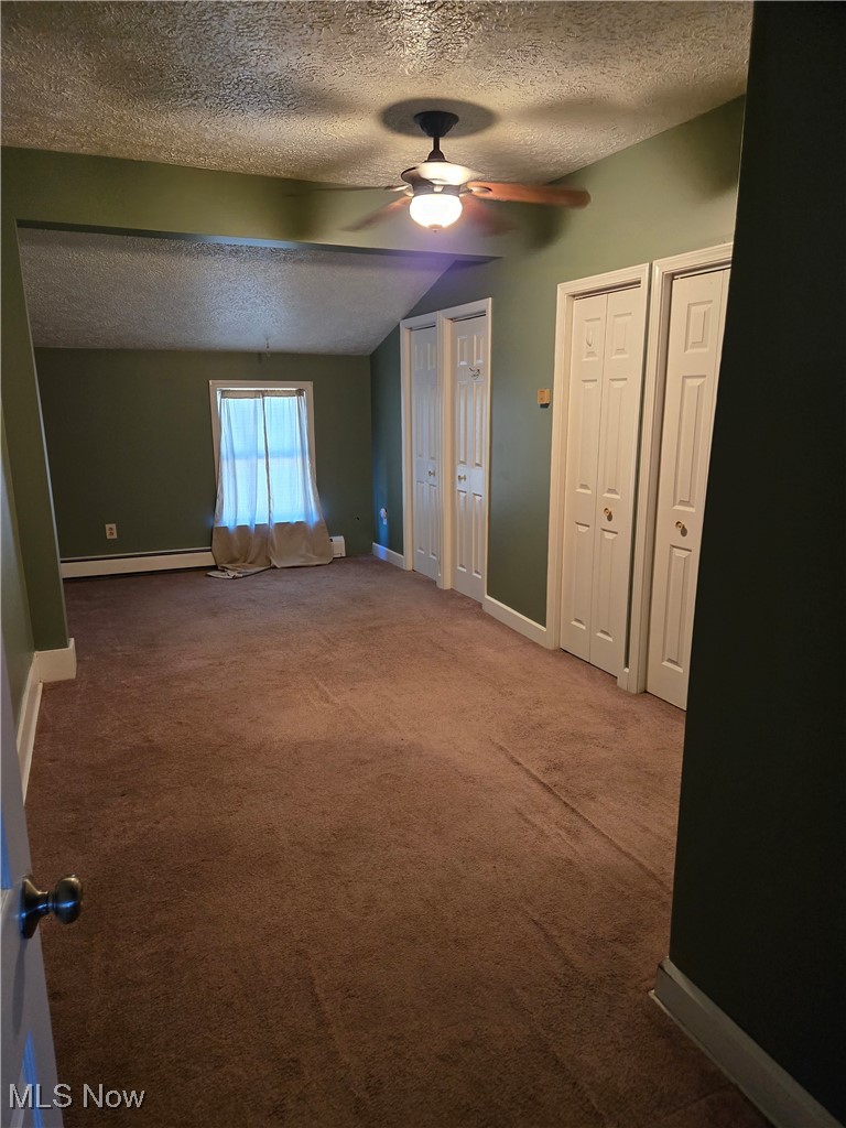 5555 Detroit Road Sheffield, OH 44054 - Photo 12 of 50 Unfurnished bedroom with a textured ceiling, carpet, vaulted ceiling, two closets, and a ceiling fan