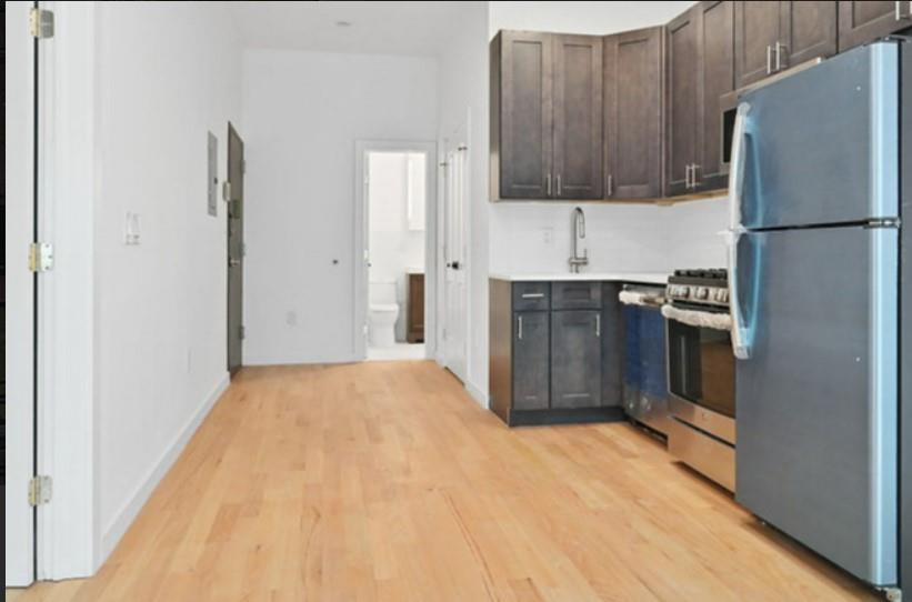 1115 Hancock Street Brooklyn, NY 11221 - Photo 5 of 33 a kitchen with granite countertop a refrigerator and a stove top oven