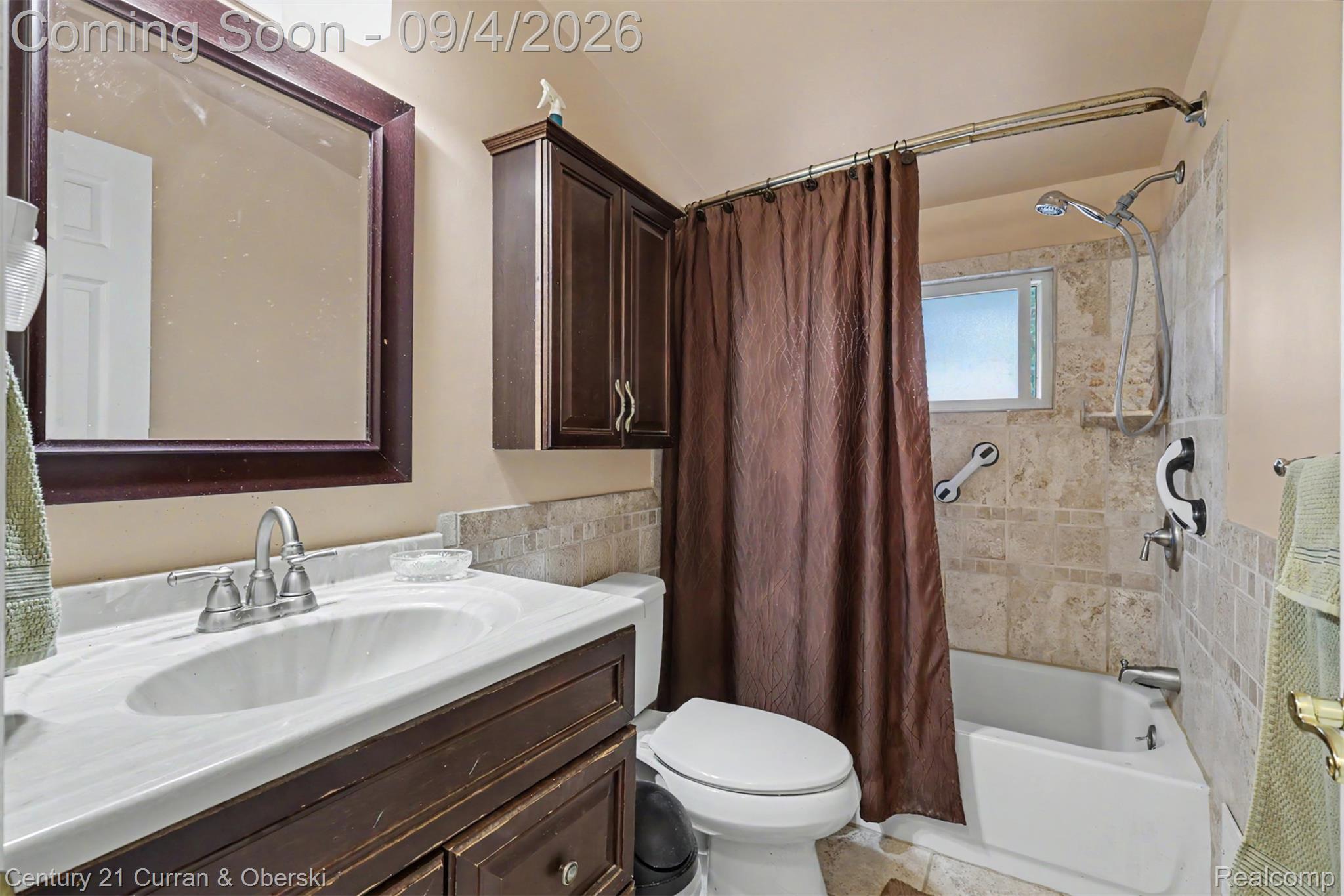 1869 Middle Trail Road Walled Lake, MI 48390 - Photo 11 of 27 Bathroom with a dark wood vanity, white countertop with integrated sink, framed mirror, and a tiled shower-tub combination
