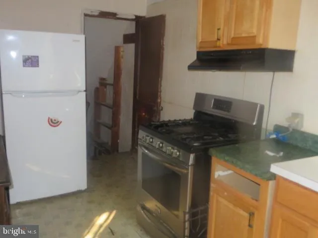 a kitchen with stainless steel appliances granite countertop a refrigerator and a stove