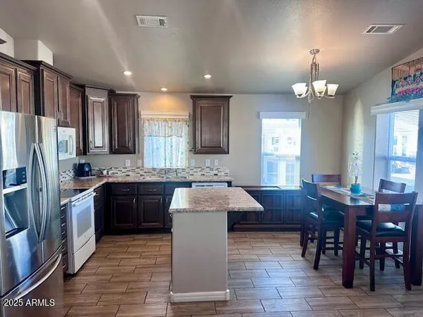 a kitchen with kitchen island granite countertop stainless steel appliances a sink stove refrigerator and cabinets