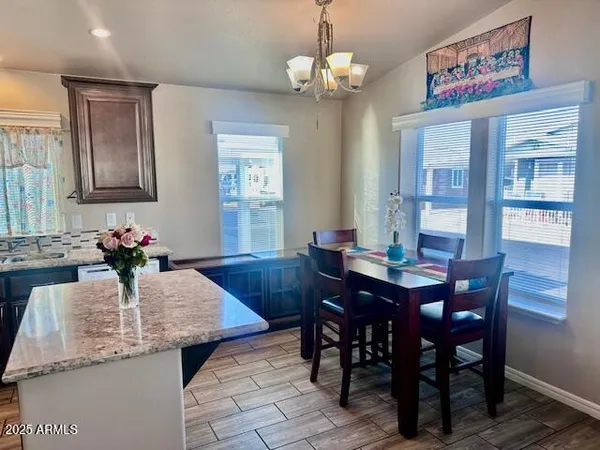 a kitchen with stainless steel appliances granite countertop wooden cabinets a refrigerator a sink a stove a dining table and chairs